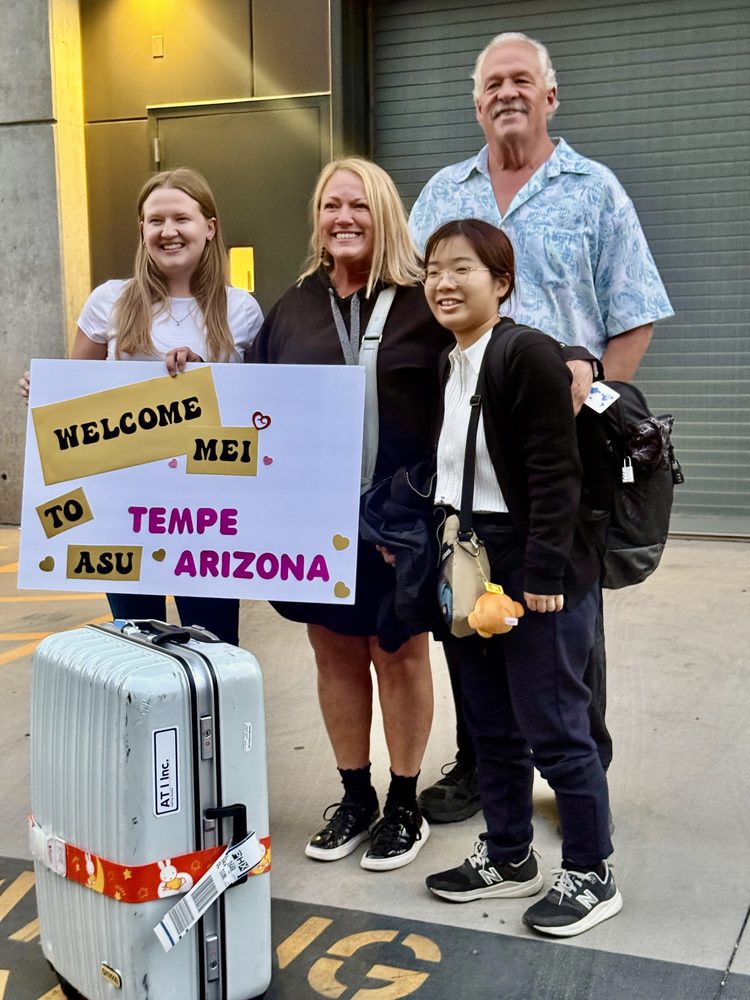 Host family welcoming student Mei at airport with welcome sign